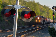 Close Up Of An Active Railroad Crossing Light With Blurred On-coming Train In Background.