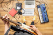 Young man playing electric guitar at rehearsal room, point of view shot. Top view of male producer at home studio playing guitar and electronic instruments.