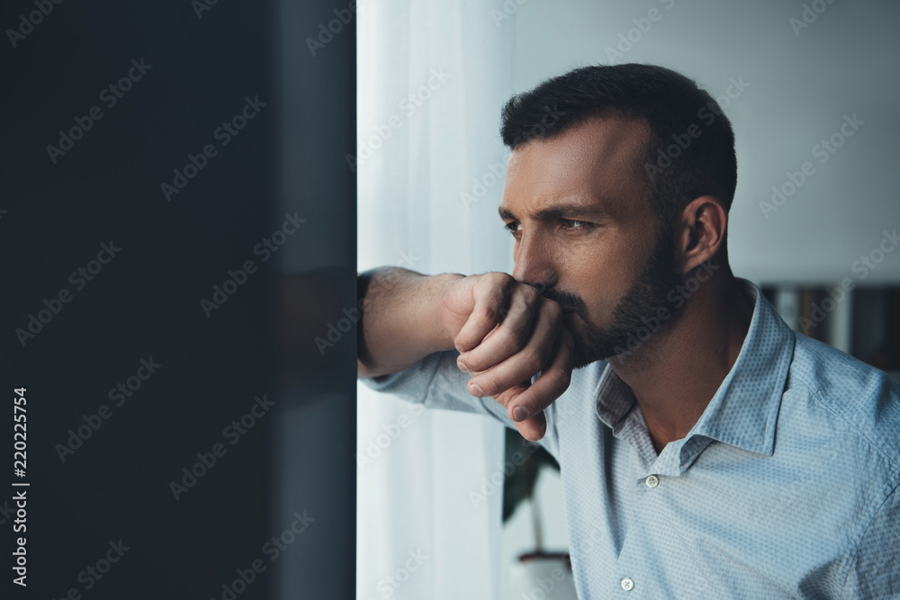 upset pensive man looking at window at home - obrazy, fototapety, plakaty 