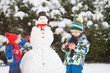 © Tomsickova - Happy beautiful children, brothers, building snowman in garden and drinking tea