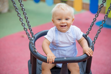 Wall Mural - Adorable baby boy, playing with different rides on the playgdorund