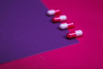 Assortment of various colourful pills on pastel coloured background.