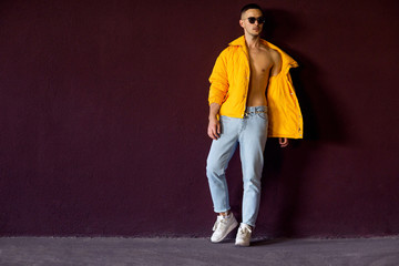 Wall Mural - fashion guy standing near a viola wall in yellow clothes