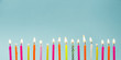 Set of many different color shape and pattern birthday candles burning in long row, isolated on blue. Happy Birthday card design concept. 