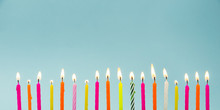 Set Of Many Different Color Shape And Pattern Birthday Candles Burning In Long Row, Isolated On Blue. Happy Birthday Card Design Concept. 