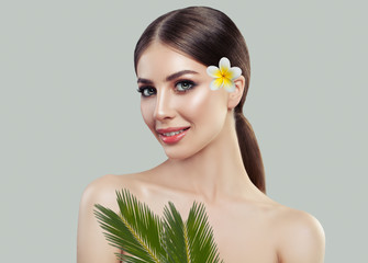 Wall Mural - Beautiful Girl with Tropical Flower and Green Leaves. Blossom Portrait of Pretty Young Woman with White Flower