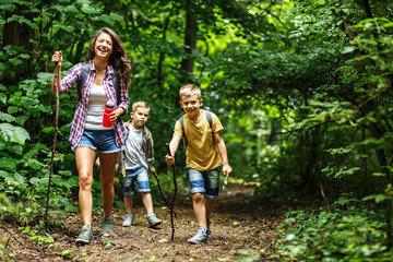 Wall Mural - mother and her little sons hiking trough forest. they're learning about nature.