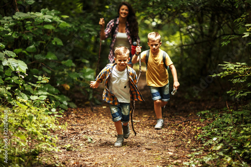 Photographie Mother and her little sons hiking trough forest