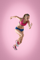 The studio shot of high jump athlete or fit woman in action i on pink background