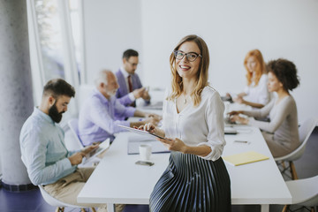 elegant businesswoman standing in office with digital tablet