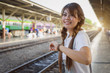 © NopponPAT - woman check time waiting for train on public railway station. travel transport concept..young  Asian girl looking at watch, standing on platform waiting for train to arrive.