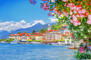 Wall Mural - Italy, Europe. Lake Como and lovely village Bellagio, view through pink flowers of oleander plant. Gorgeous travel background of traditional italian small towns, lake Como is popular summer resort.