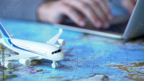 Fotografía Airplane model closeup, defocused person booking flight tickets online on laptop