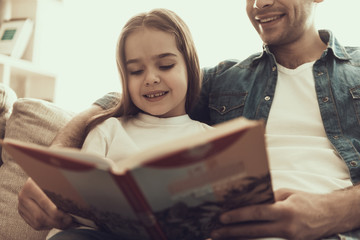 Fototapete - Young Smiling Man Reading Book to Little Girl