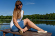 © Uladzimir - Woman at sea, lake. Cute woman on a wooden bridge over blue water on a sunny day