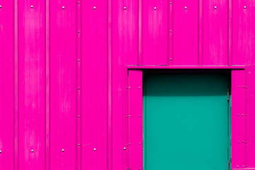 Modern industrialism. Neon pink building with green door. Vibrant paint color choice.