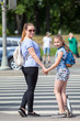 © Kekyalyaynen - Mom and daughter holding hands on pedestrian crossing, waiting green light. Looking at camera