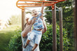 © olgasparrow - Young father and a blond boy in blue T-shirts climb the stairs at the children's playground in the summer.