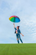 © songphon - Asian woman holding colorful umbrella jumping in to the blue sky.