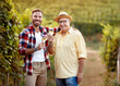 © luckybusiness - smiling father and son tasting wine in vineyard.
