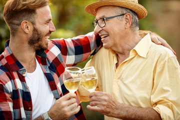 Wall Mural - happy father and son tasting wine in vineyard.