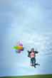 © songphon - Asain woman holding colorful balloons and jumping in to blue sky  and white clouds background.