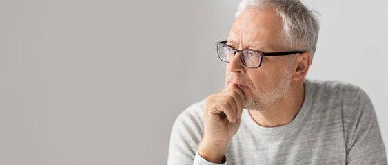 old age, problem and people concept - close up of senior man in glasses thinking