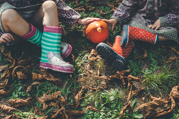cropped image of children with boots and a little pumpkin. autumn and fall concept