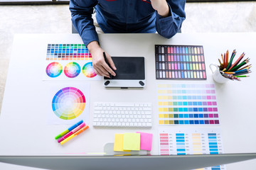 Poster - Image of male creative graphic designer working on color selection and drawing on graphics tablet at workplace with work tools and accessories, top view workspace