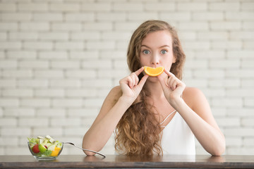 Beautiful young woman in joyful postures with salad bowl on the side