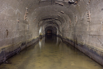 Underground abandoned gold iron ore mine shaft tunnel gallery passage with timbering wooden flooded water