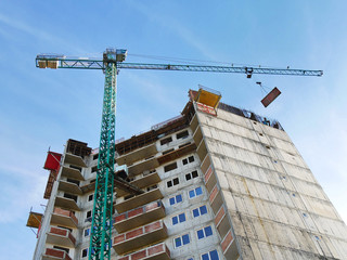 Hoisting crane near building. Building under construction. Construction site.