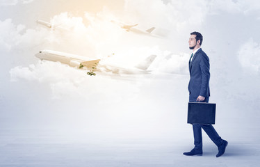 Elegant businessman going somewhere with briefcase and airplane on the background
