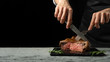 Chef, cut with a meat steak on a black background with an open space for text or restaurant menus. Horizontal photo Black text area.