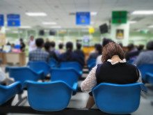 Young Woman Sit On Blue Chair At Front The Emergency Room And Many People Waiting Medical And Health Services To The Hospital,patients Waiting Treatment At The Hospital,blurred Image Of People