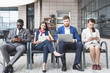 © xartproduction - Group of happy diverse male and female business people team in formal gathered around laptop computer in bright office against the background of a glass building
