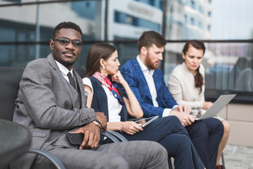 Wall Mural - Group of happy diverse male and female business people team in formal gathered around laptop computer in bright office against the background of a glass building