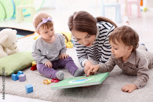 Fotomural Young nanny with cute little children, indoors