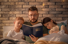 Father Reading Bible To His Li...