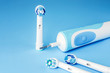 Modern electric toothbrush and spare heads on blue background