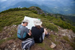 © Melinda Nagy - male hiker friends checking map while sitting on a mountain peak