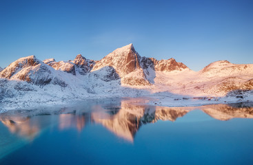 Canvas Print - Aerial view at the mountains and reflection on the water surface. Lofoten islands, Norway. Natural landscape during sunrise from air. Drone landscape