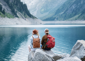 Wall Mural - Travelers couple look at the mountain lake. Travel and active life concept with team. Adventure and travel in the mountains region in the Austria