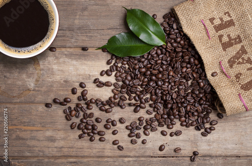 Photographie Kaffeesack mit Kaffeebohnen und Kaffeetasse auf Holzbrett