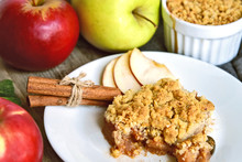 Apple Crumble On With Dish With Spoon And Fresh Green And Red Apple With Cinnamon Stick On Wooden Floor. Easy And Basic Dessert Menu.
