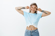 © Cookie Studio - Smile to camera and live to fullest. Happy positive woman in trendy oufit with tattooed arms, showing victory or v sign over eyes, smiling broadly, being in playful mood expressing friendly attitude