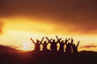 Happy friends with raised arms sunset silhouettes