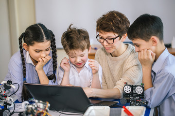 group of happy kids with their female adult science prof with tablet pc computer programming electri