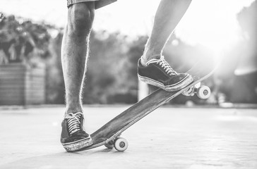 Skater performing with longboard at sunset in urban city square - Young trendy man having fun with skateboard - Extreme sport concept - Black and white editing