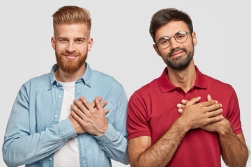 Wall Mural - Thankful two guys keeps both hands on heart, show gratitude gesture, recieve words of praise for good work, being thankful for this, have thruthful friendship, isolated over white background